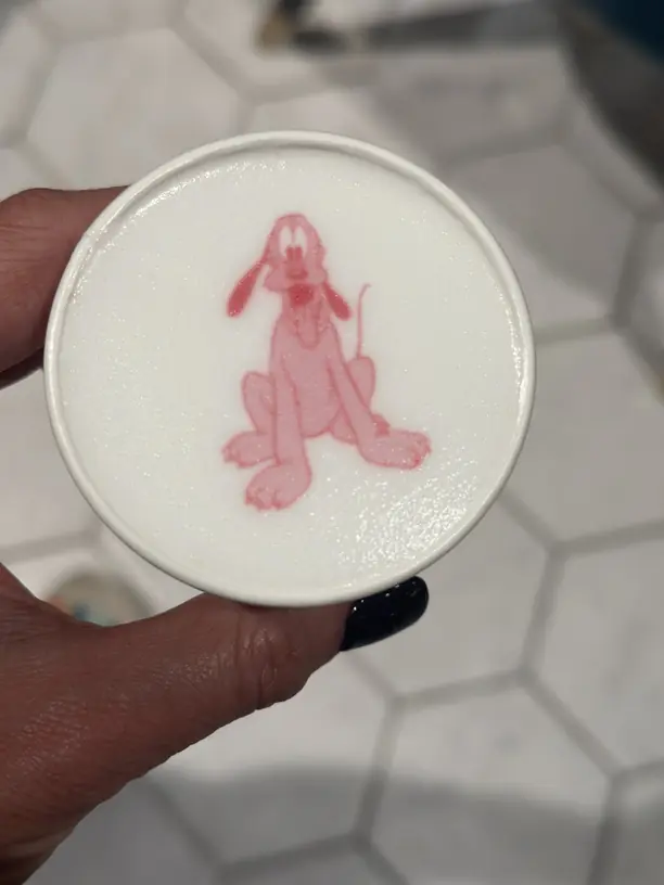 A latte with Pluto printed on the foam on a Disney cruise