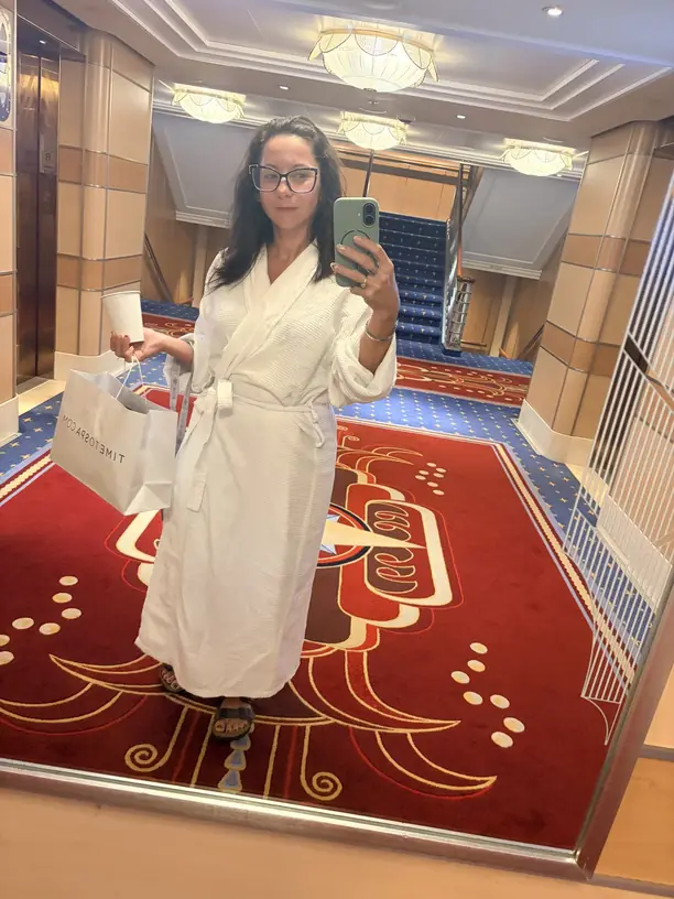 Nicole in a spa robe with coffee heading to the spa on a Disney cruise