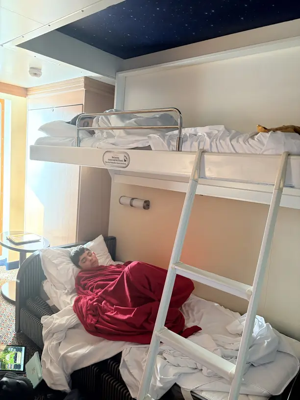 Two boys asleep in the pull down bunk and sofa bed of a Disney cruise stateroom for a family of five