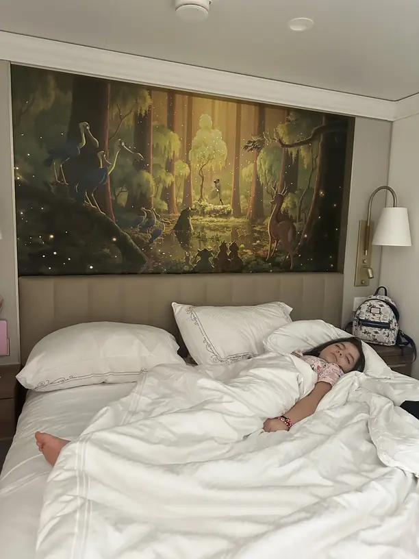 Avilene asleep in a Disney cruise stateroom under a Princess and the Frog mural