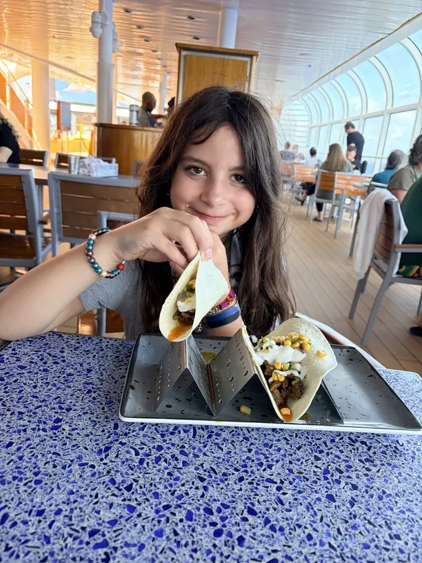 Avilene holding up tacos on the pool deck of a Disney cruise