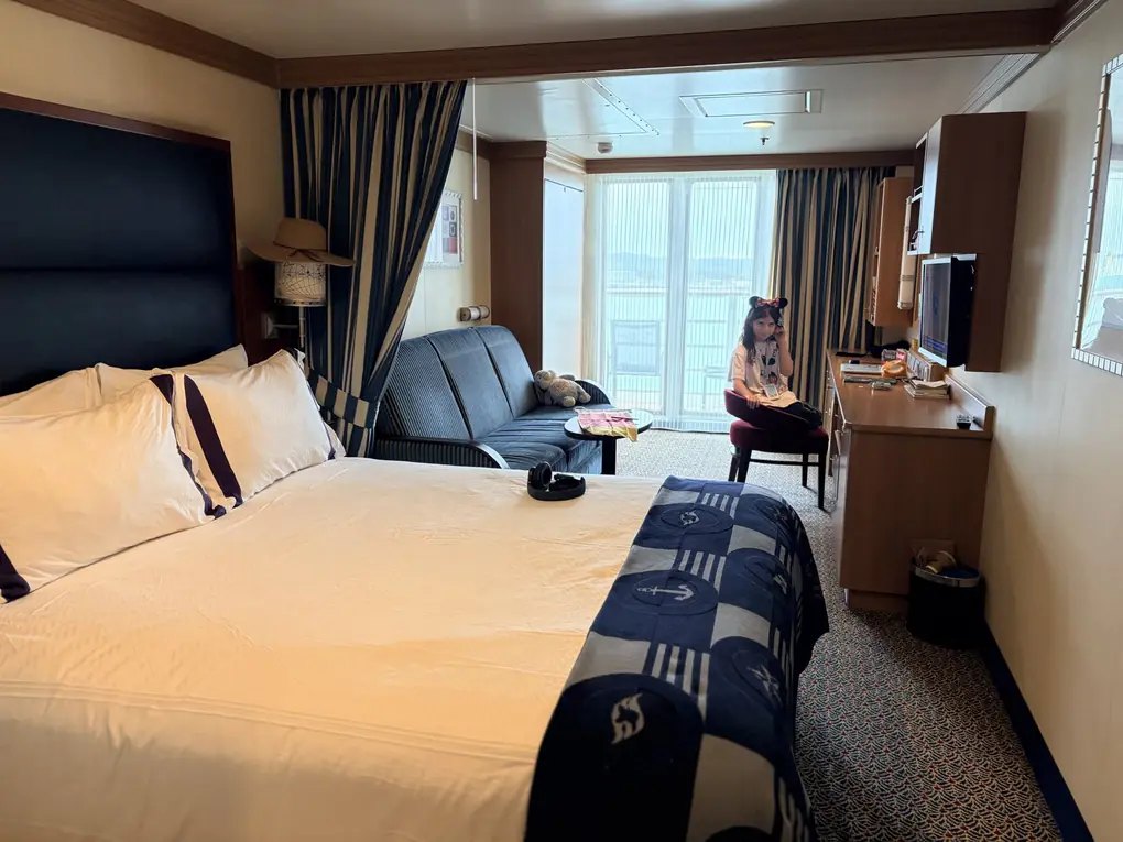 A Disney cruise verandah stateroom with queen bed, sofa bed and balcony doors
