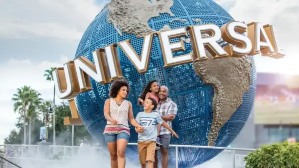 A family walks past the spinning Universal globe at the entrance to Universal Orlando Resort