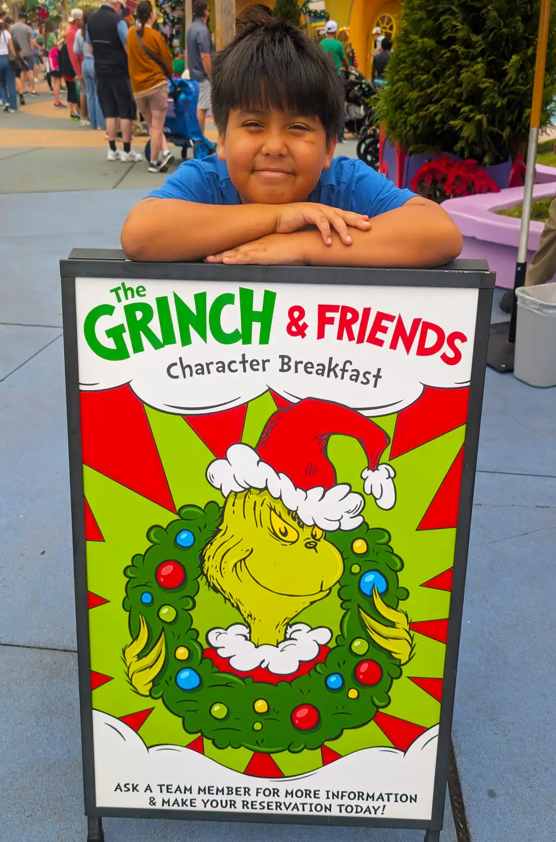 Grinch and Friends Character Breakfast Sign at Universal Orlando - Favorite Grampy Travels A young guest leans on the Grinch and Friends Character Breakfast sign outside Circus McGurkus Cafe at Universal Islands of Adventure