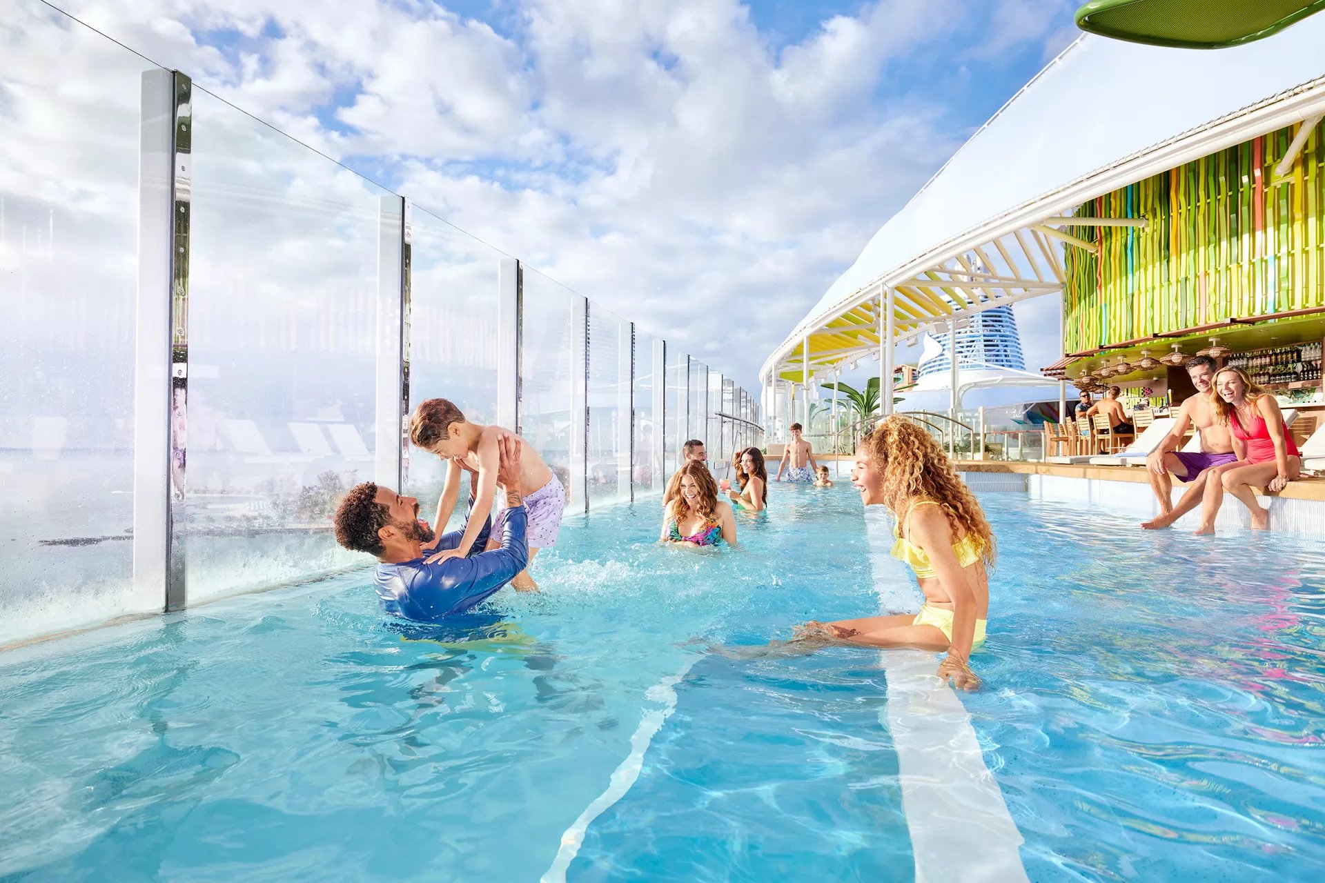 Families swimming in the Cloud 17 pool beside the glass windscreen on Icon of the Seas