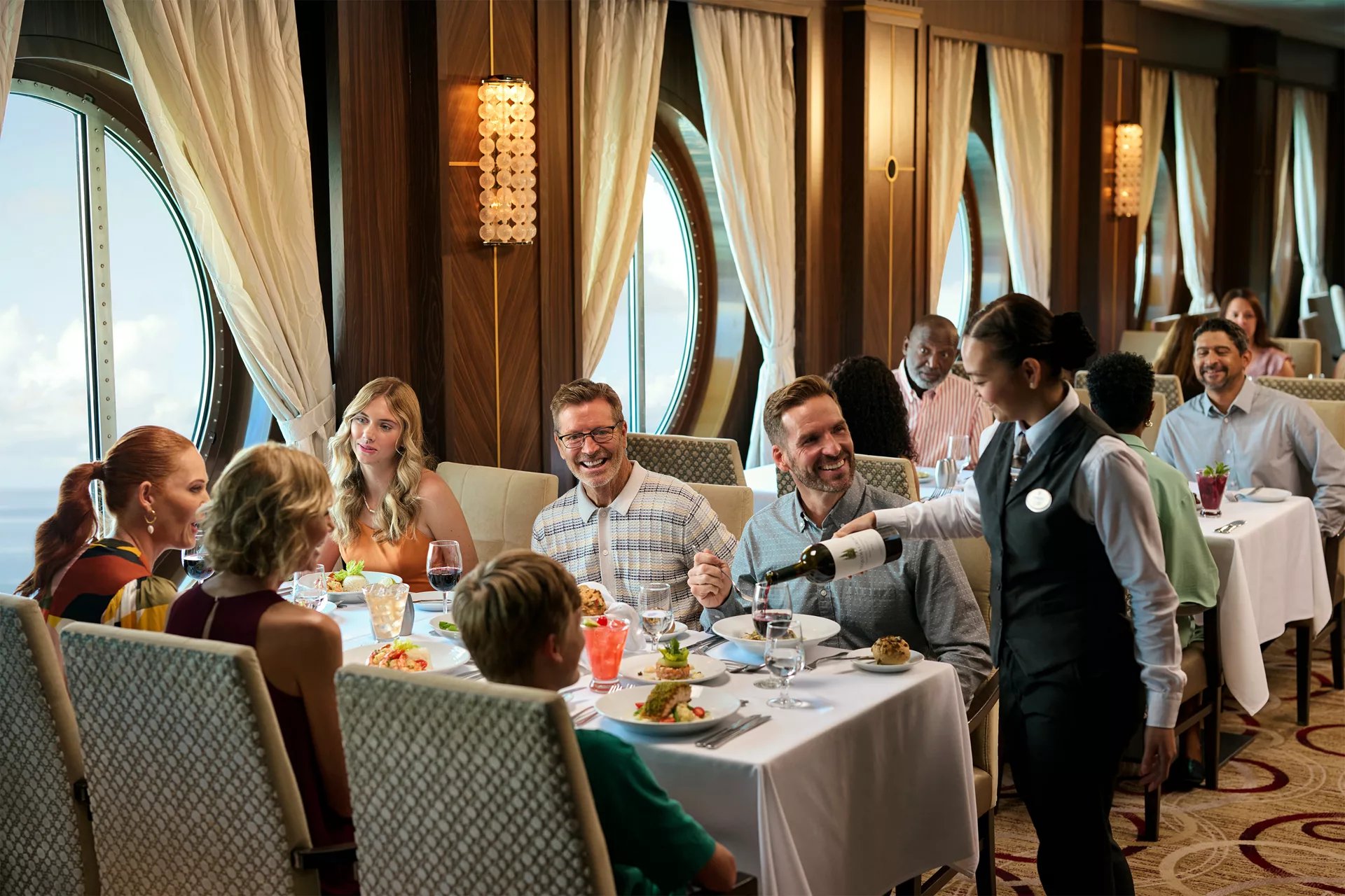 Family having dinner while a server pours wine in a Royal Caribbean main dining room