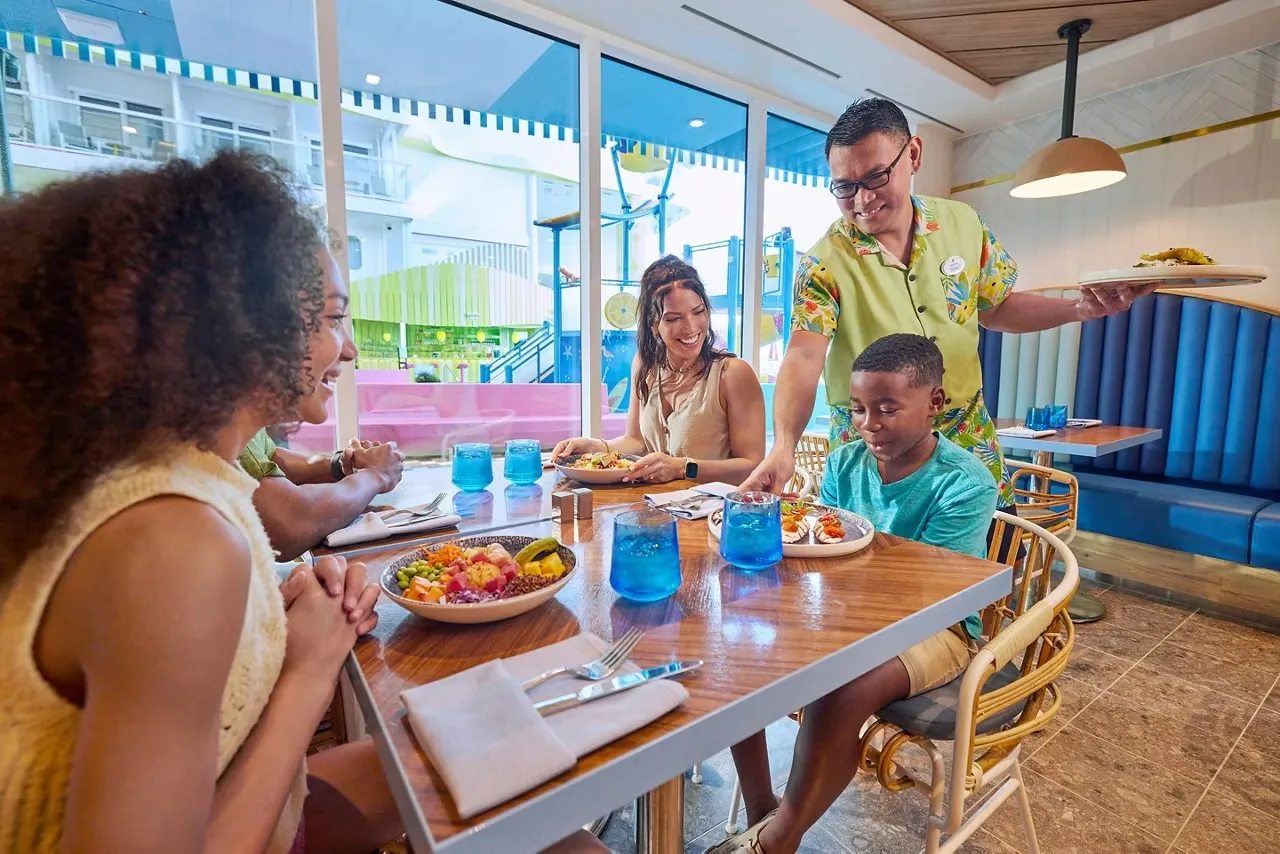 Family being served lunch at a window table in Pier 7 restaurant on Icon of the Seas