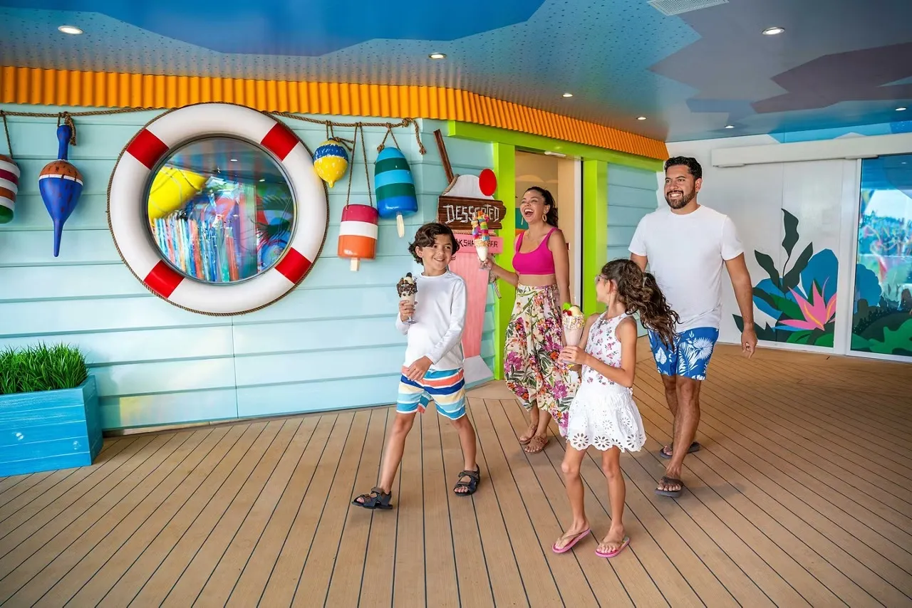 Family with two children walking the Surfside boardwalk holding ice cream cones on Icon of the Seas