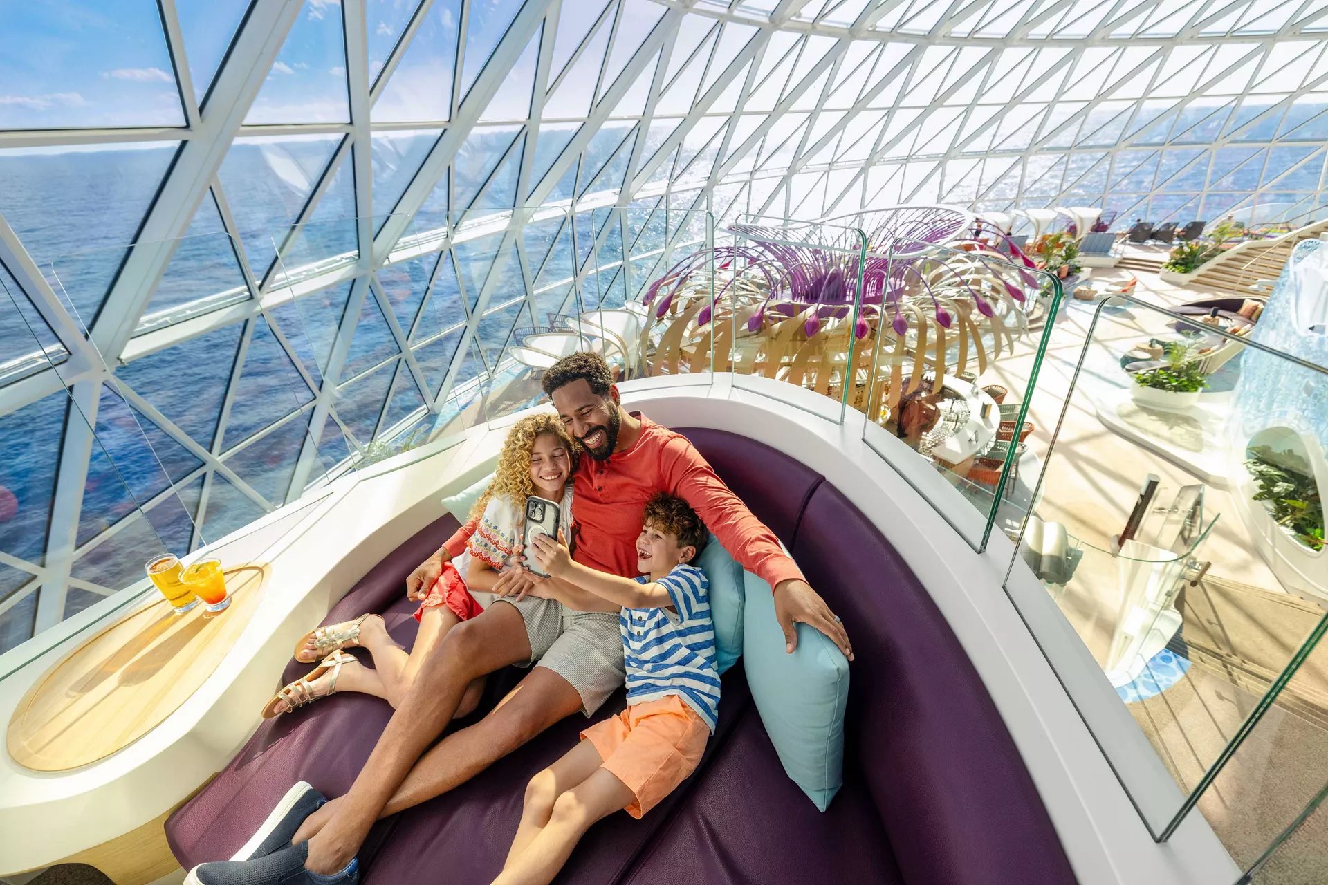 Father and two kids taking a selfie at The Overlook lounge on Icon of the Seas