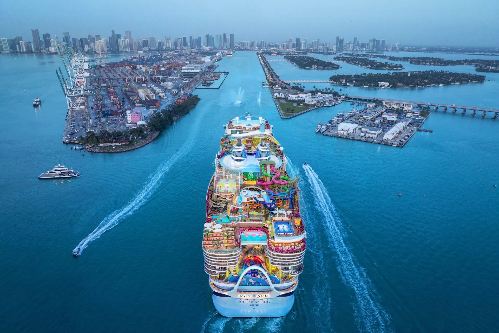 Aerial view of Icon of the Seas sailing in the channel at PortMiami with the Miami skyline behind