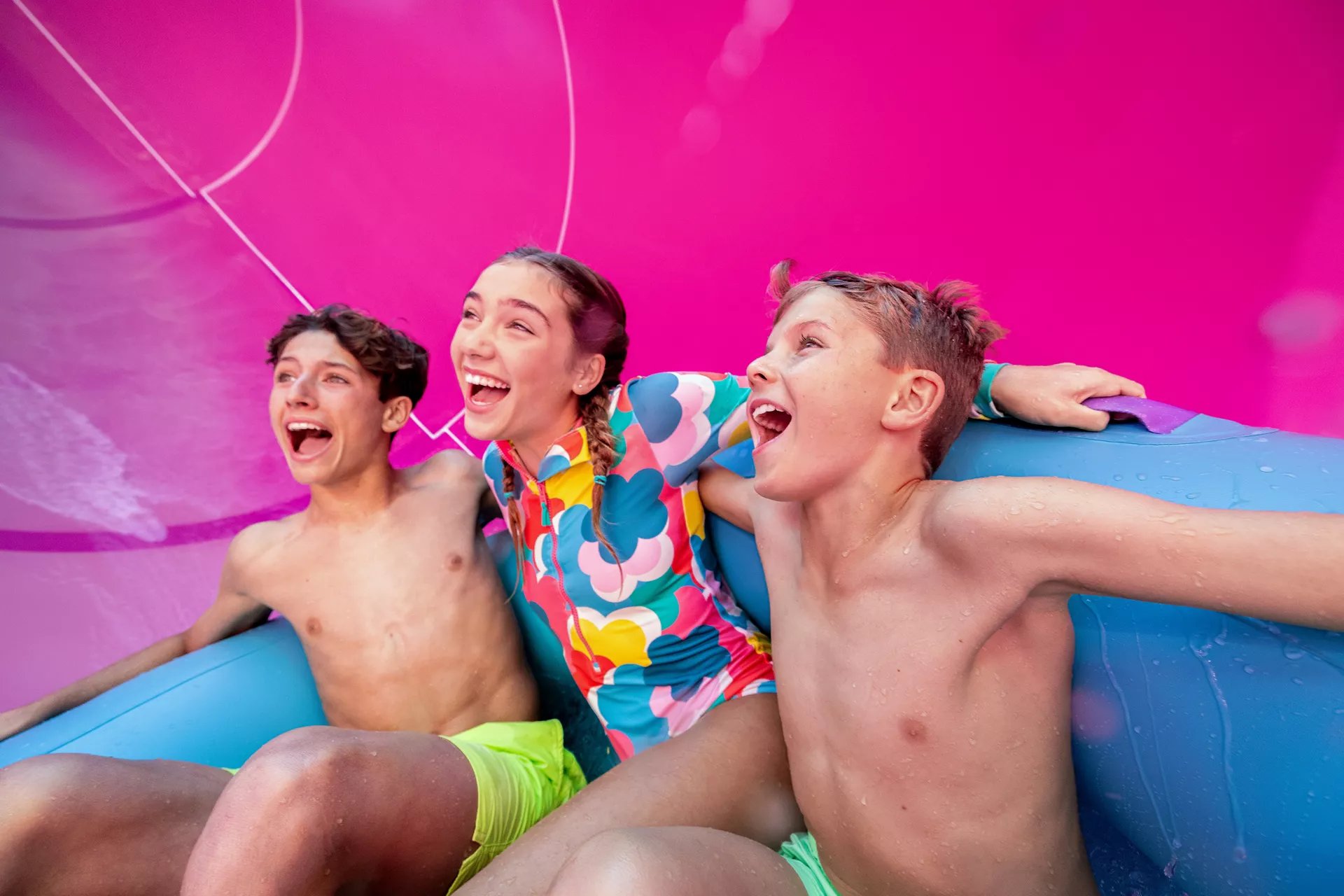 Three kids laughing on a raft on the Hurricane Hunter waterslide at Category 6 on Icon of the Seas