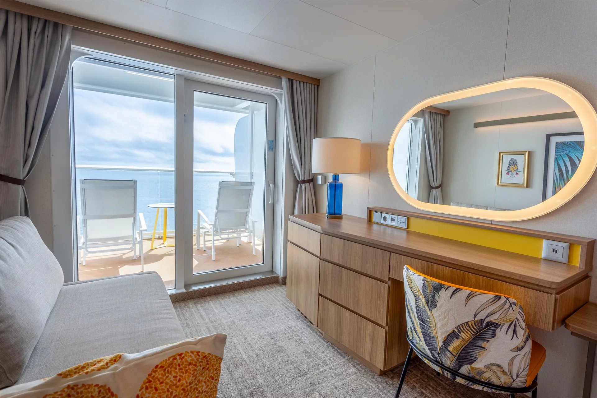 Sofa, vanity and sliding door to the balcony in an Ocean View Large Balcony stateroom on Icon of the Seas