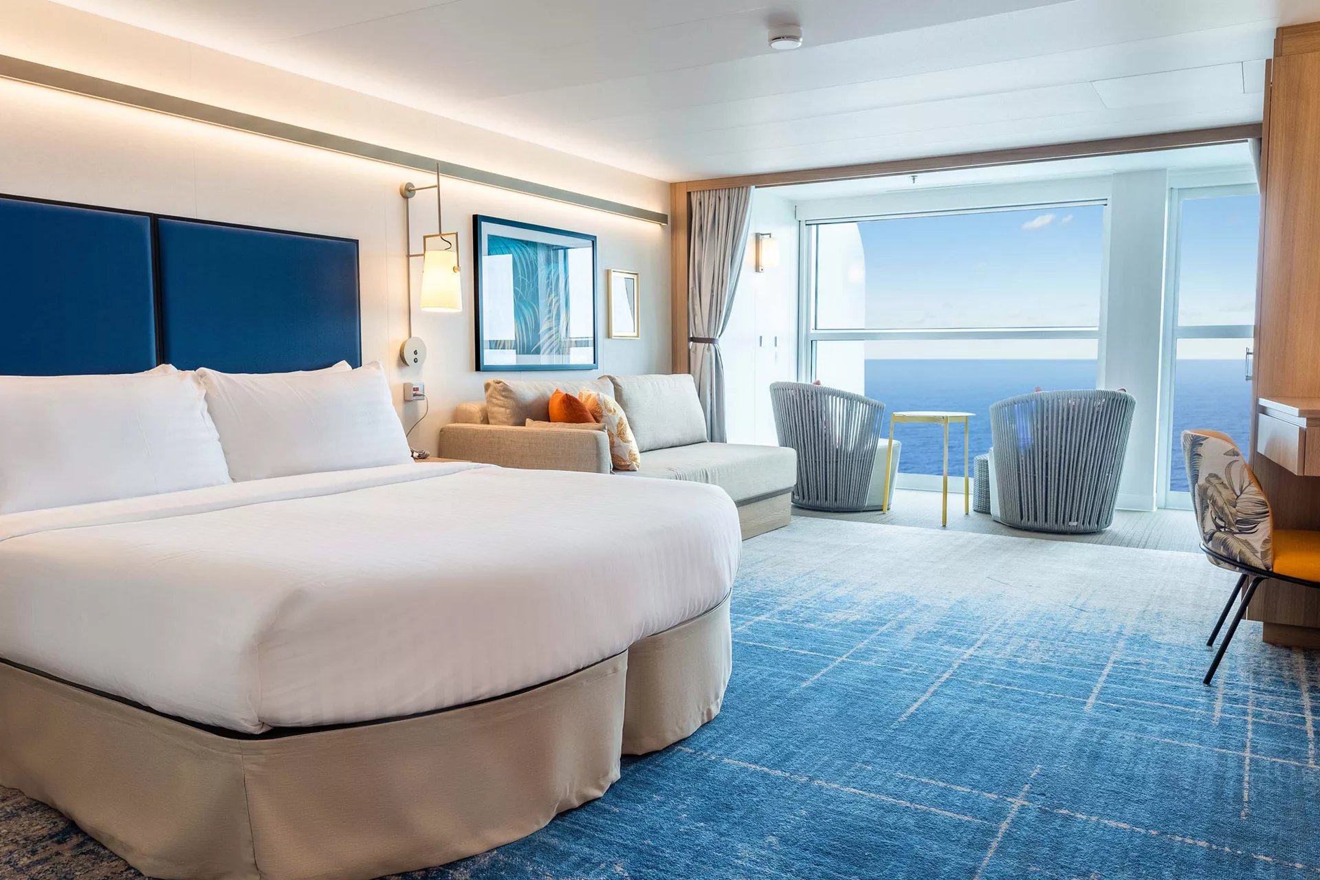 Bed and sitting area of a Spacious Infinite Ocean View Balcony stateroom on Icon of the Seas