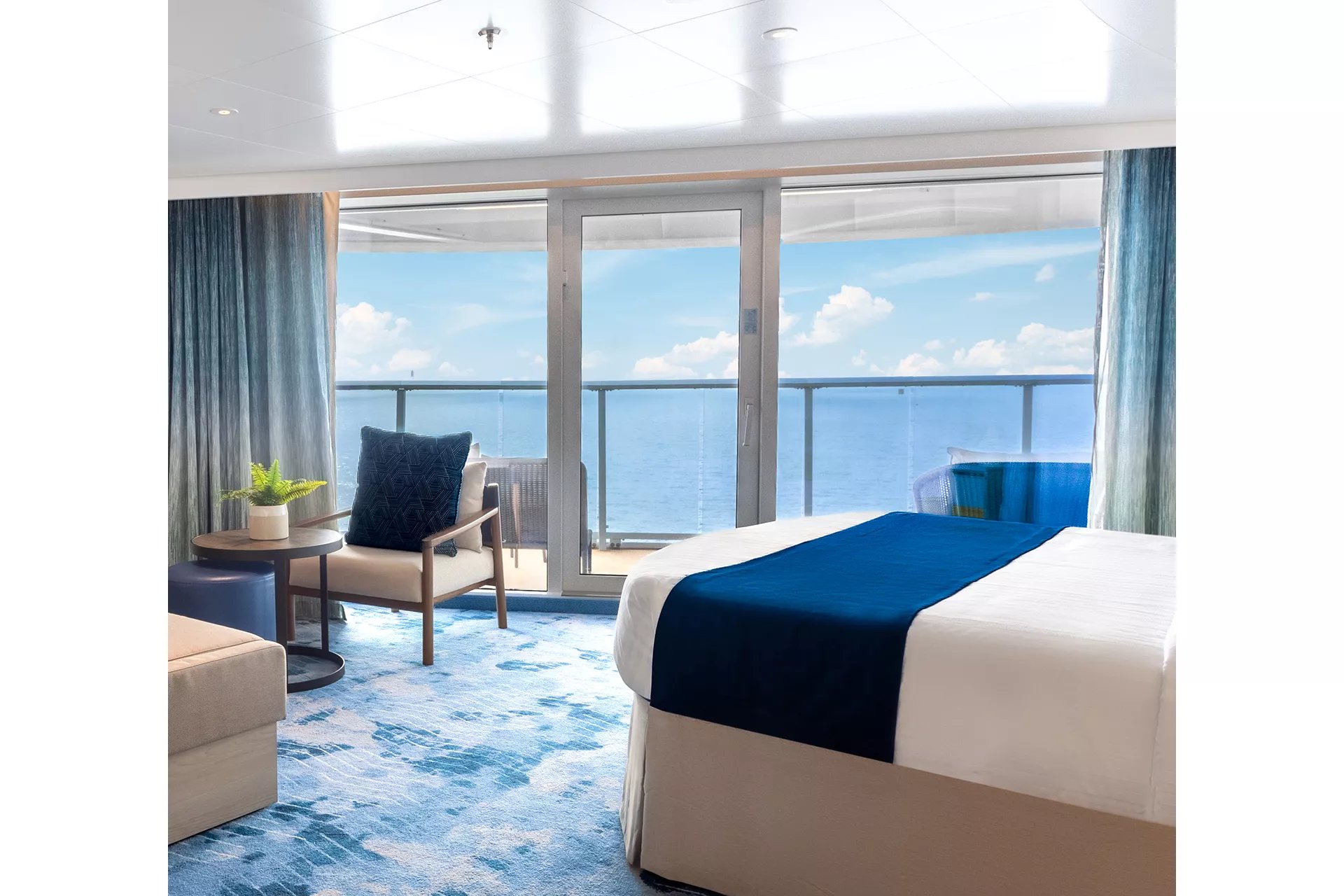 Bed facing the wraparound ocean balcony in a Sunset Corner Suite on Icon of the Seas
