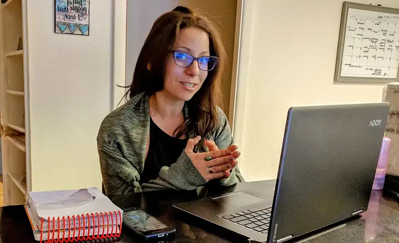 Favorite Grampy Travels advisor at her desk with a laptop, phone and notebook, planning a family vacation