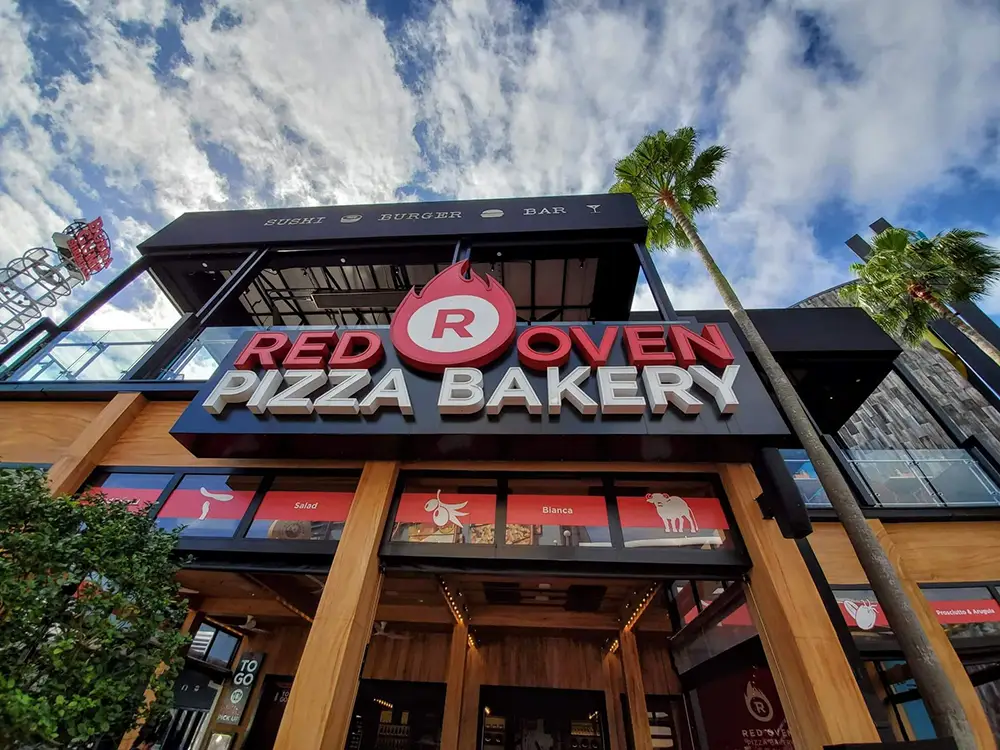 Red Oven Pizza Bakery restaurant exterior at Universal CityWalk, featuring a large sign and menu descriptions visible on the windows. - Favorite Grampy Travels