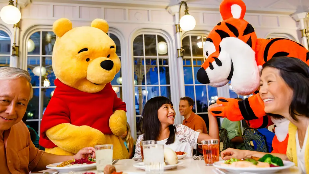 Winnie the Pooh and Tigger visit a family at their table during a Disney World character meal. - Favorite Grampy Travels
