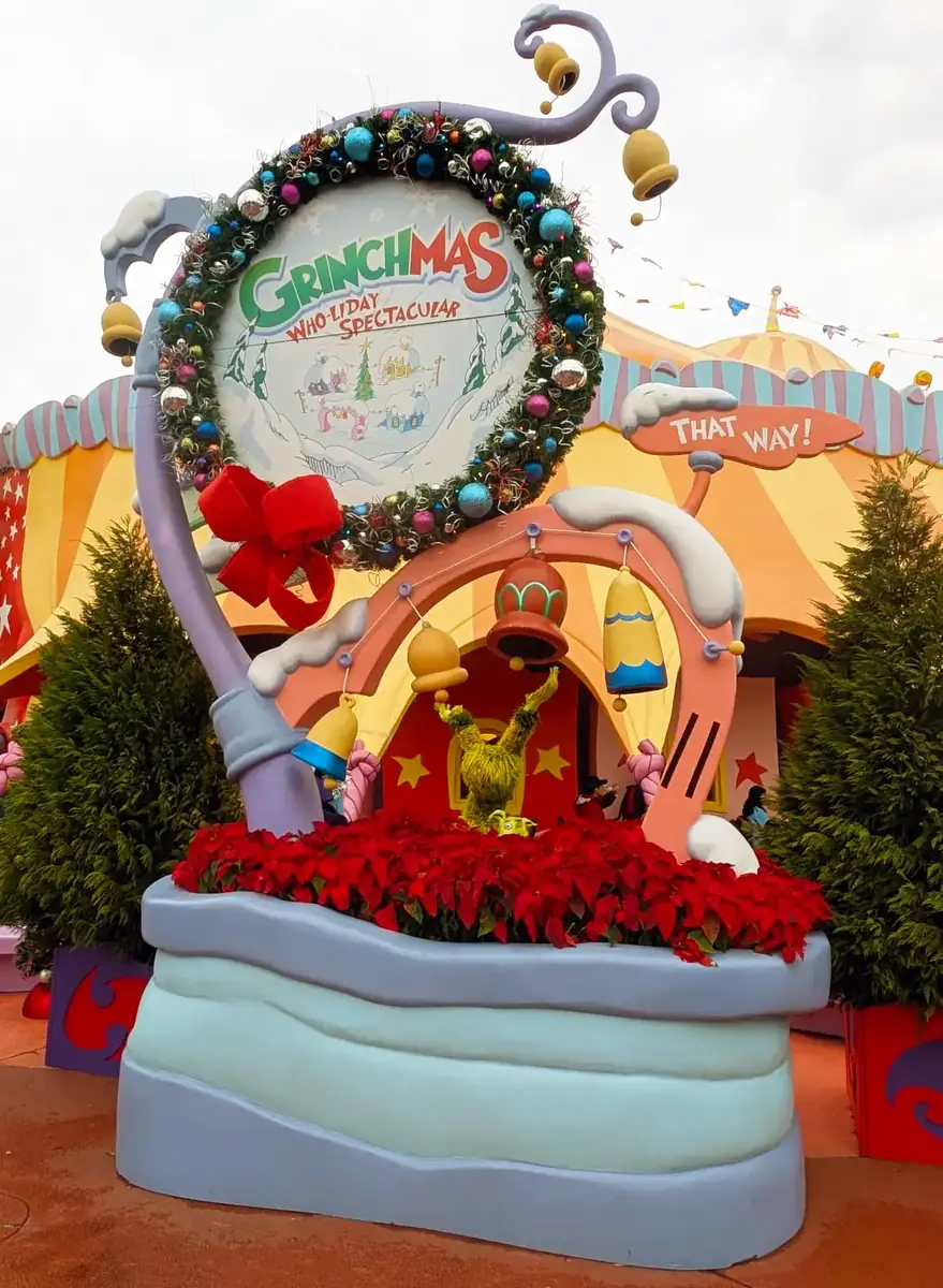 Grinchmas Who-liday Spectacular wreath sign with red bow and poinsettias outside the theater in Seuss Landing at Universal Islands of Adventure