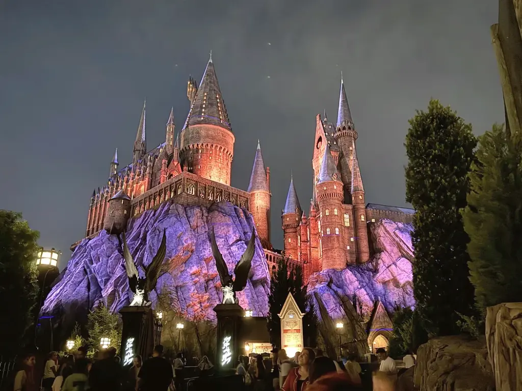 Hogwarts Castle glowing purple and red at night in Islands of Adventure at Universal Orlando - Favorite Grampy Travels