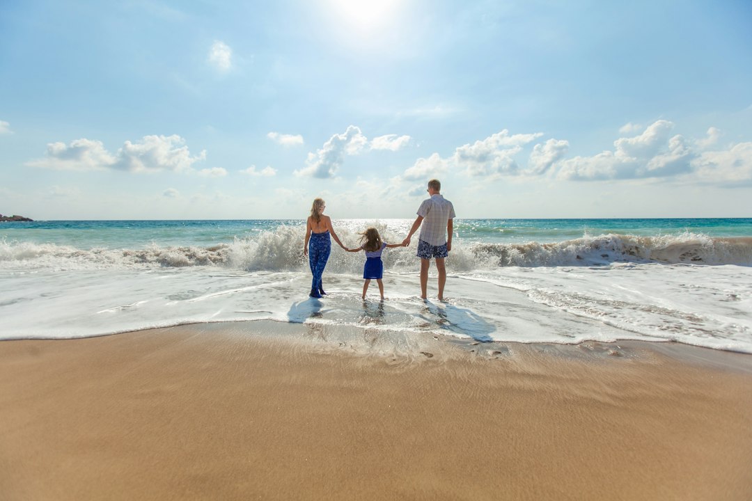 Family holding hands and walking into the ocean surf together on a beach vacation