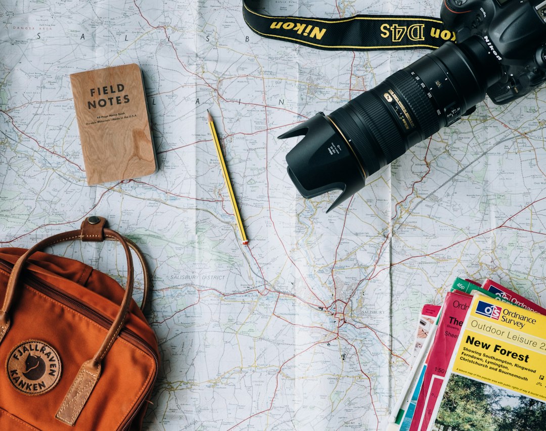 Travel map, camera and backpack laid out on a table while planning a personalized family vacation
