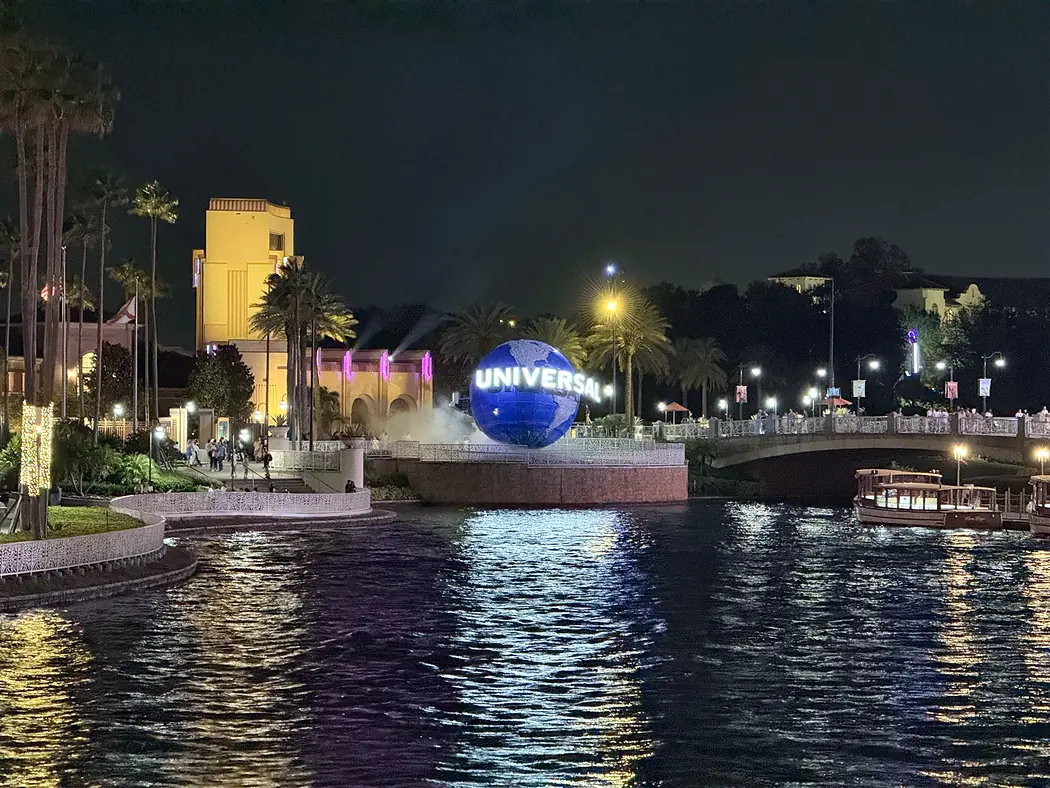 The Universal globe lit up across the CityWalk lagoon at night at Universal Orlando - Favorite Grampy Travels